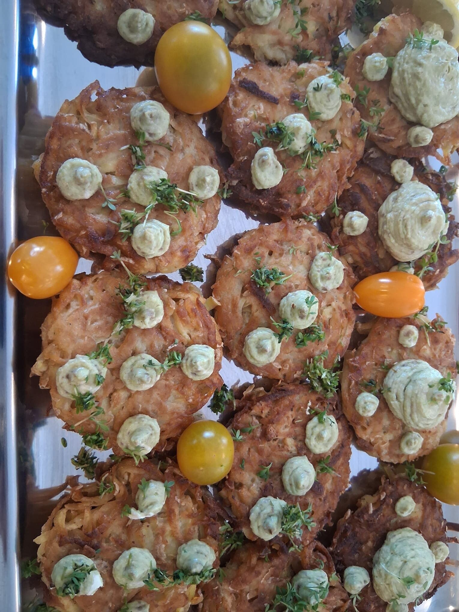 Goldbraune Bratlinge mit hellgrüner Creme, Kräutern und Mini-Tomaten