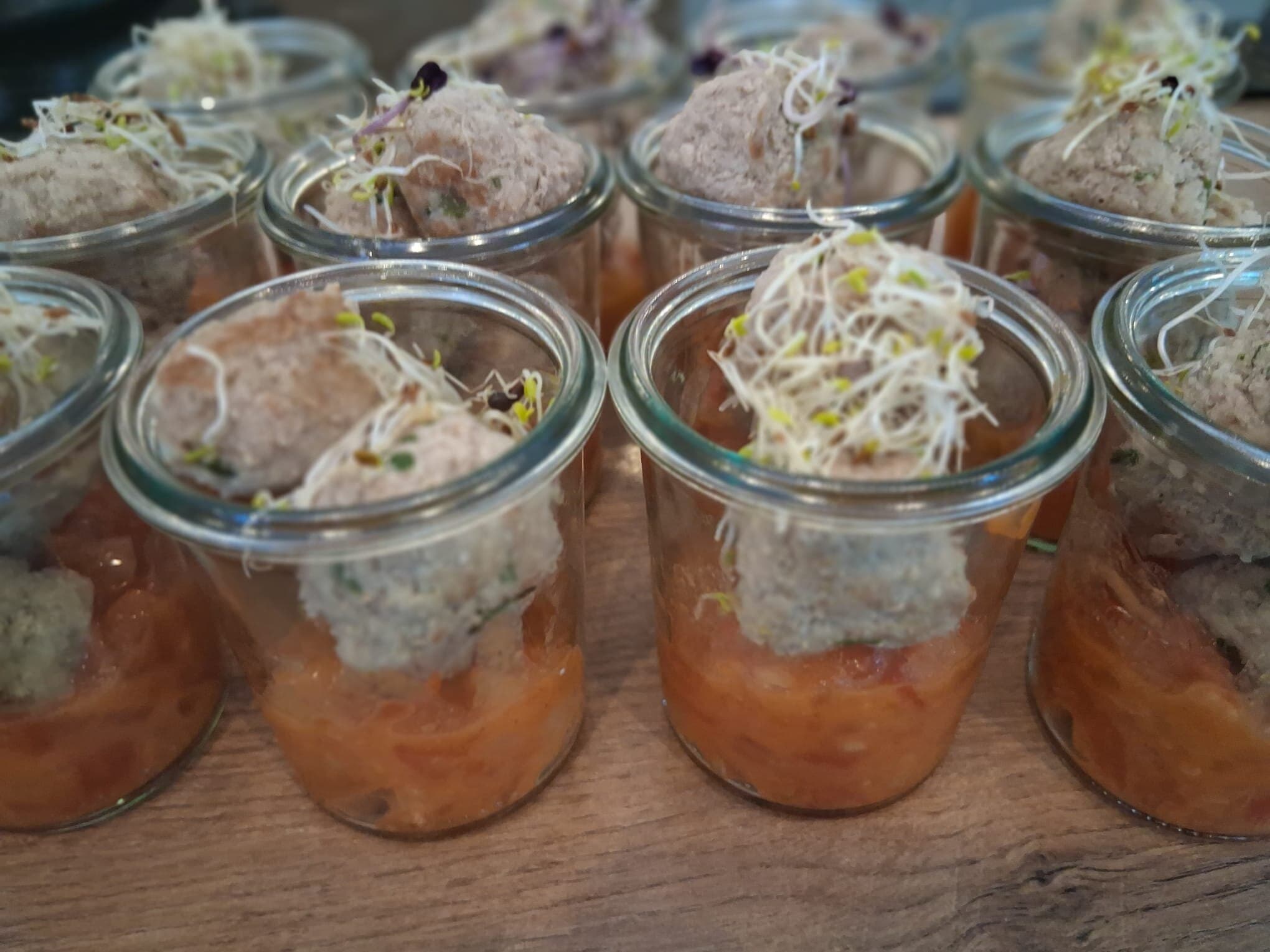 Vorspeisen in Gläsern: oranges Püree, helle Kugel, Sprossen, lila Blüte