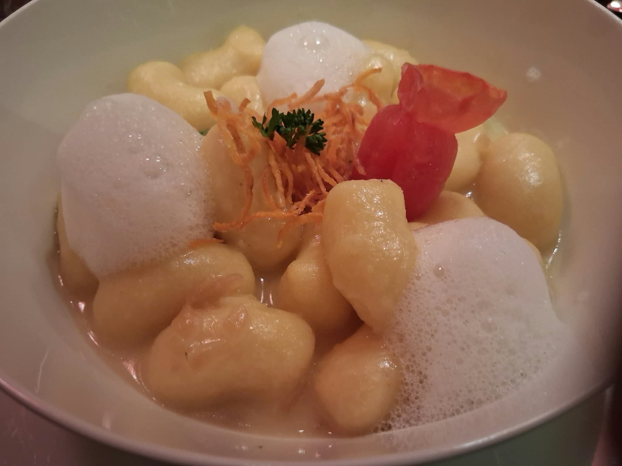 Klösschen in heller Sauce mit Schaum, Kräutern und Tomate
