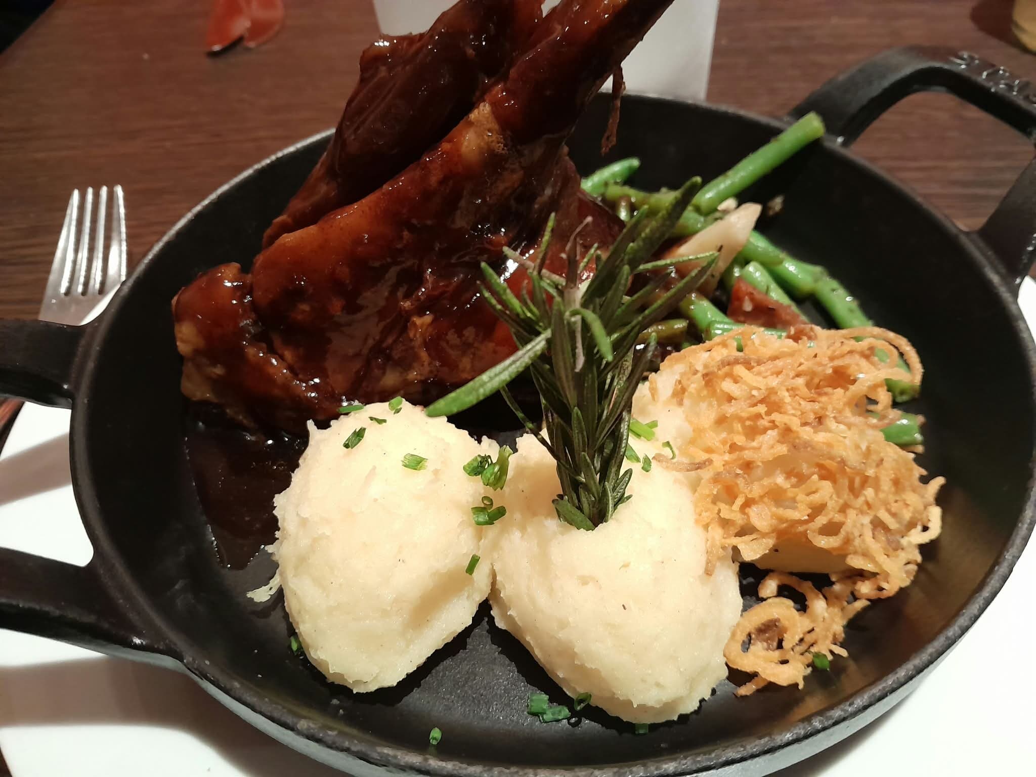 Fleisch in gusseiserner Pfanne mit Bohnen, Kartoffelpüree und Röstzwiebeln